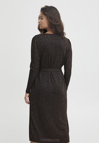 Vestito nero a maniche lunghe in tessuto testurizzato con strisce verticali, vita aderente e lunghezza al ginocchio.
