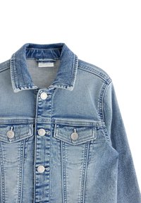Helles blaues Denim-Jacke mit klassischem Kragen, zwei Brusttaschen und silbernen Beschlägen. Der Stoff weist subtile Ausbleichungen und Abnutzungsspuren auf.