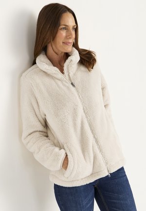 Fleece jack in crème kleur met een ritssluiting, hoge kraag en zijzakken. Zachte textuur en relaxte pasvorm met lange mouwen.