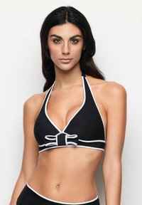 Svart halterneck bikinitopp med vita detaljer, trekantig kupform och rosett i mitten. Slät tyg med en åtsittande design.