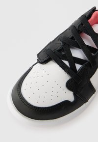 Μαύρο και λευκό αθλητικό παπούτσι με τρυπητή λευκή μύτη, μαύρο δέρμα στην επάνω πλευρά, μαύρες γκέτες και ροζ επένδυση εσωτερικά. Καουτσούκ σόλα.