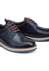 Zapatos de cuero azul marino con acentos marrones, puntera redonda, cordones en contraste naranja y azul, media suela blanca con detalles marrones, suela de goma.