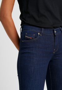 Mörkblå denimjeans med slim fit, med en liten framlapp med kontrastsöm och en märkesetikett på midjan.