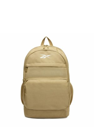 Mochila color marrón claro con bolsillos frontales con cremallera, bolsillos laterales de malla, asa superior y logotipo blanco de Reebok sobre tela lisa.