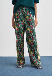 Φαρδιά παντελόνια με floral τύπωμα σε μαύρο φόντο, με πράσινα, κόκκινα και κίτρινα λουλούδια. Διαθέτουν πλευρικές ρίγες και ελαστική μέση.