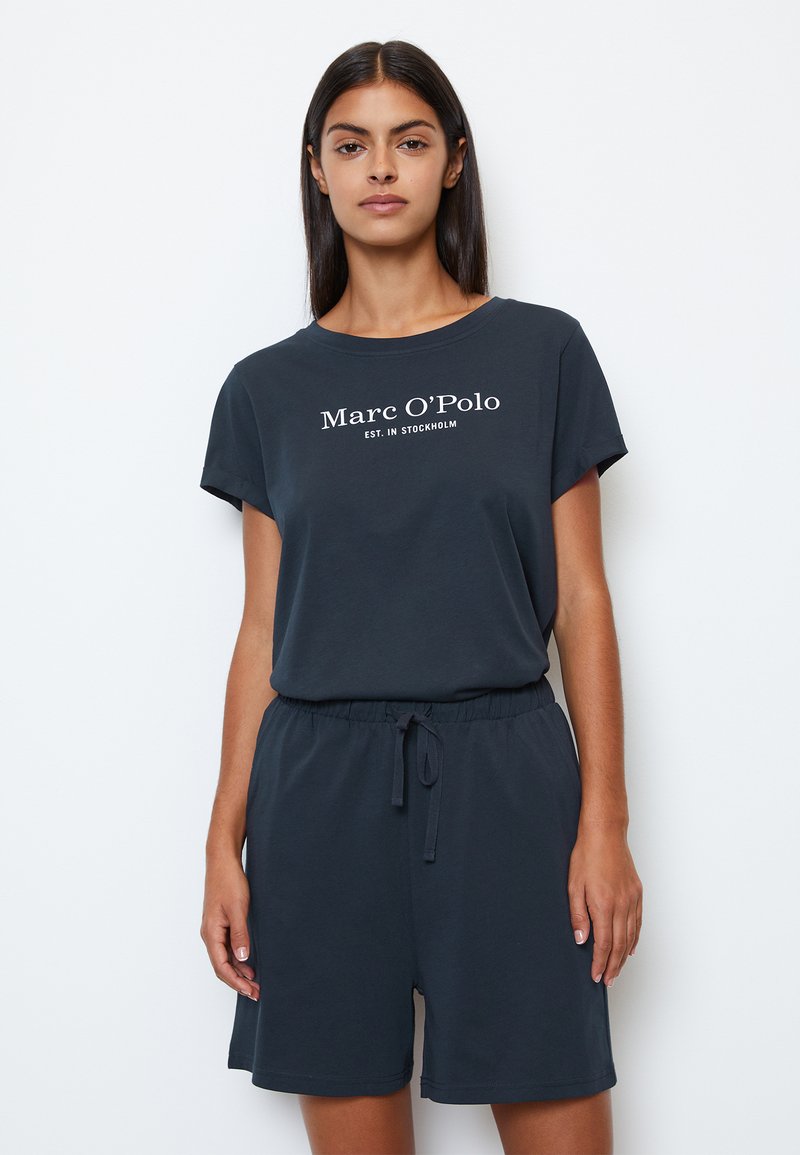 Marineblauw t-shirt met korte mouwen en bijpassende shorts set. T-shirt heeft witte merklogo tekst; de shorts hebben een elastische tailleband met trekkoord.