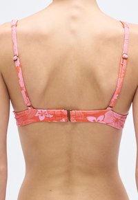 Pink floral-patterned bikini top with a textured finish, adjustable straps, and a metal clasp closure at the back.
