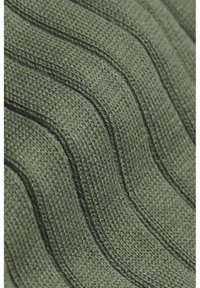 Getextureerde groene gebreide stof met golvende ribbels, die een zacht garenmateriaal en een consistent patroon van contrasterende lijnen toont.
