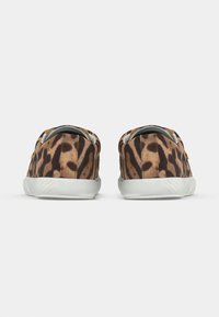 Ζευγάρι χαμηλά αθλητικά παπούτσια με επάνω μέρος από ύφασμα σε καφέ και μαύρο λεοπάρ σχέδιο και λευκές λαστιχένιες σόλες, φαίνεται από πίσω.