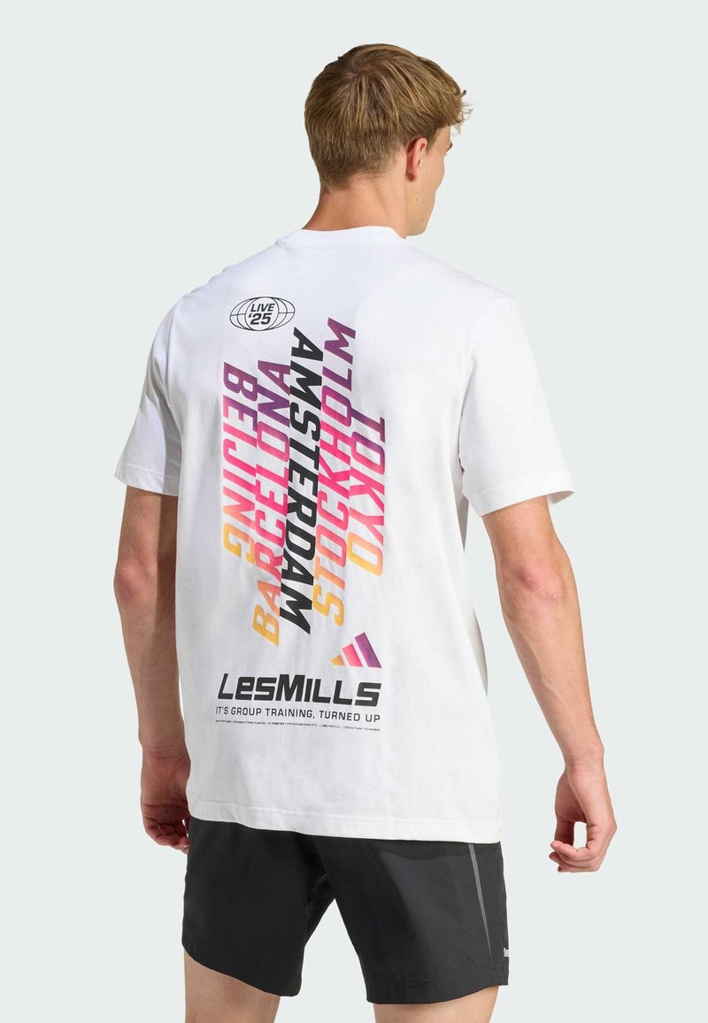 Camiseta de algodón blanca con tipografía colorida y audaz en la parte posterior, que muestra nombres de ciudades y el logo "LesMILLS" en negro. Mangas cortas, corte relajado.