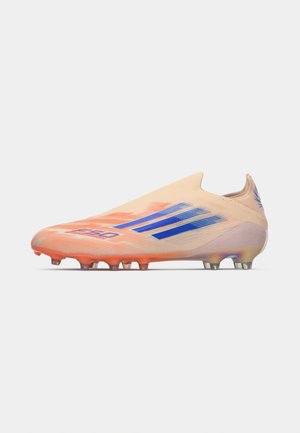Helle orange Fußballschuhe mit blauen Streifen, orangefarbenen Stollen und "FSLO"-Branding an der Seite, im Seitenprofil dargestellt.