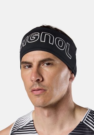 Man met een zwarte hoofdband met witte "SIGNOL" tekst en een zwart-wit gestreept sportshirt, kijkt met een neutrale uitdrukking vooruit.