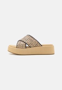 Beige plattform-sandaler med korslagda remmar som har ett geometriskt mönster i svart. Texturerad sula för bra grepp.