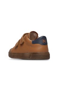 Sneaker in pelle marrone con fibbie in velcro, accentuazione del tallone blu navy, suola in gomma testurizzata e punta arrotondata. Caratterizzato da un design semplice e pulito.