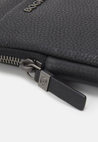 Pochette in pelle nera con superficie testurizzata, dotata di una cerniera metallica, dettaglio del logo e un elegante manico della cerniera.