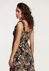 Rochie florală neagră și bej, cu bretele volanțate, un corset ajustat și o fustă evazată cu un model texturat.