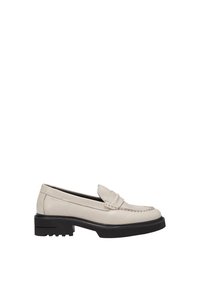 Mocassin en cuir beige avec semelle noire épaisse, bout arrondi et détails cousus le long de la tige.
