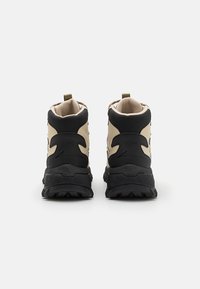 Tan and black mid-cut hiking boots feature a rugged sole, textured upper, padded collar, and a pull tab at the heel for easy wear.