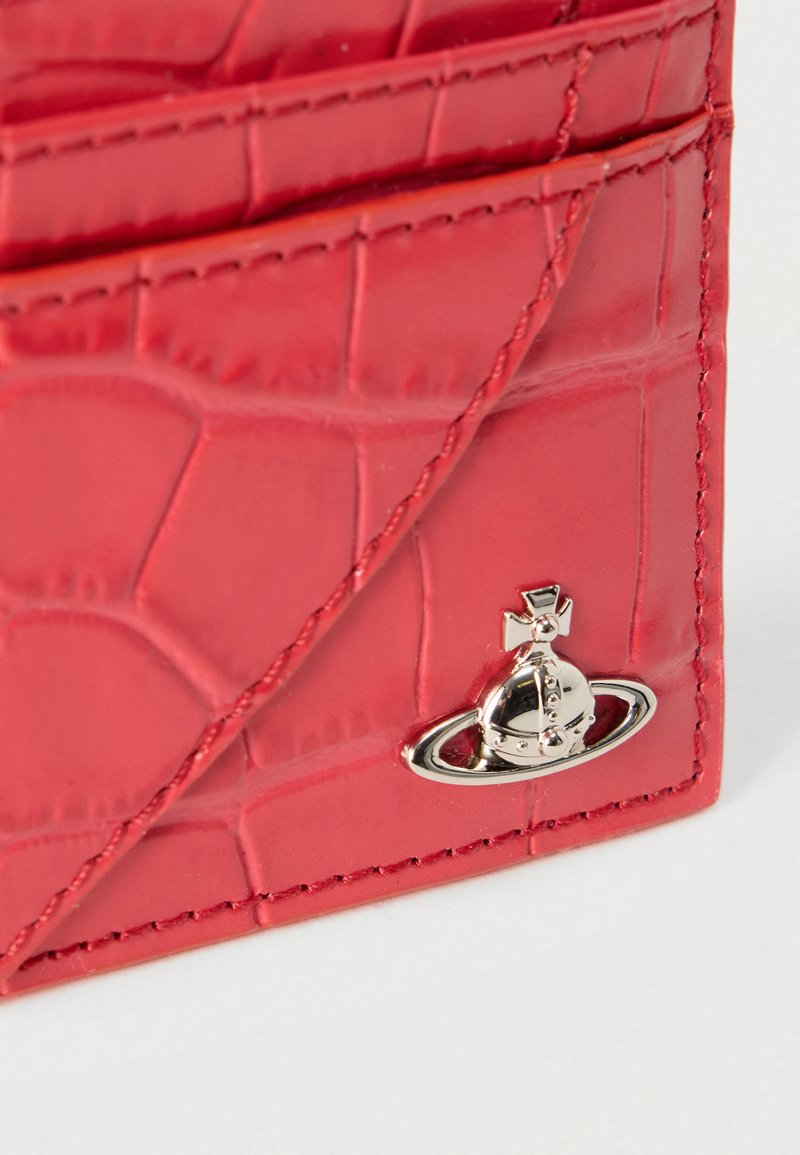 Porte-cartes en cuir synthétique rouge imitation crocodile doté de plusieurs emplacements, d'un accent en métal argenté avec un motif de planète, et d'une texture lisse.