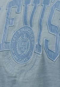 Hellblaues Levi's T-Shirt mit gesticktem Logo und Gründungsdatum, mit glatter Textur und Rundhalsauschnitt.