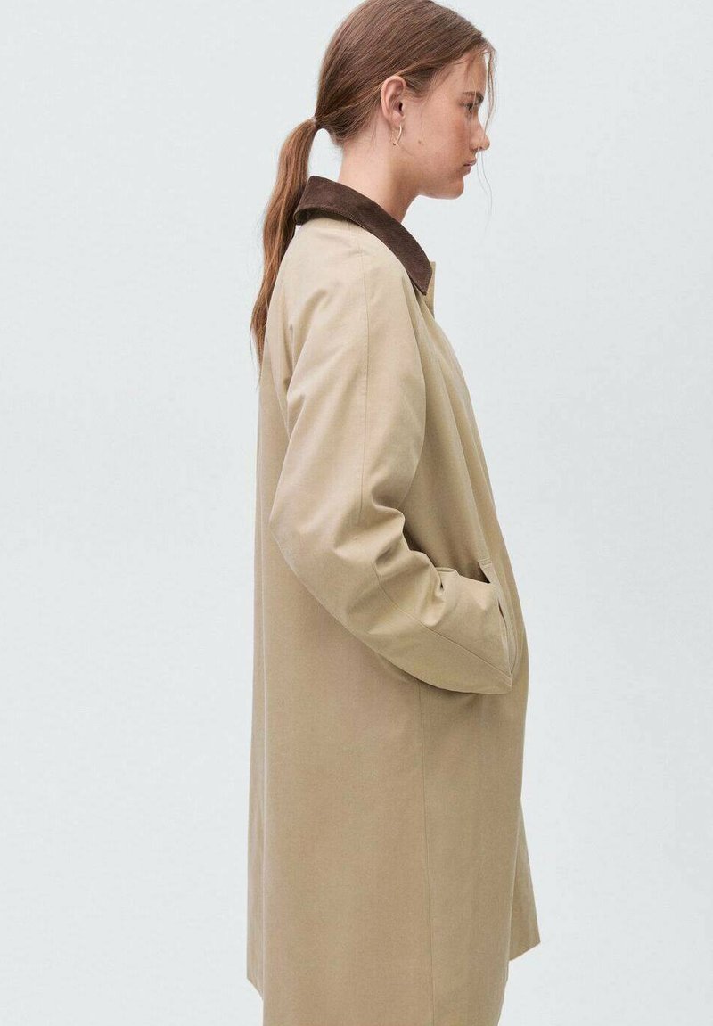 Bežna bunda s smešnim ovratnikom, z ravnim krojem, dolgimi rokavi in stranskimi žepi. Gladka tkanina z mat zaključkom.