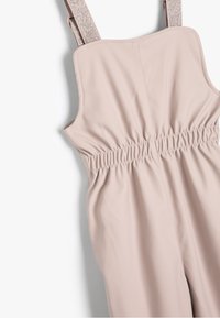 Rosa jumpsuit lavet af glat stof med samlet talje, med justerbare metalremme og vid udskæring.