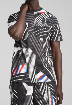 Czarna koszulka sportowa z siateczkową strukturą, z odważnym abstrakcyjnym wzorem w białych, czerwonych i niebieskich akcentach, okrągłym dekoltem i krótkimi rękawami.