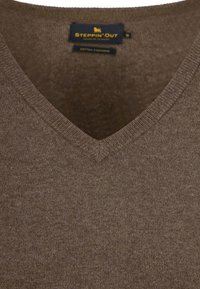 Bruine katoenen v-hals trui met een ribbelkraag en een gladde textuur, voorzien van een label met de tekst "Steppin' Out, Cotton Leisure."