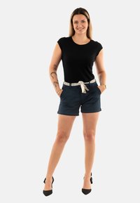 Zwart T-shirt met korte mouwen gecombineerd met marineblauwe shorts. De outfit heeft een gemonteerd riem en zwarte hoge hakken, wat zorgt voor een casual uitstraling.