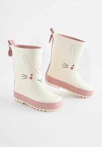 Bottes de pluie blanches en caoutchouc avec des accents roses, présentant un design de visage de lapin, des semelles texturées et des poignées pour un enfilage facile.