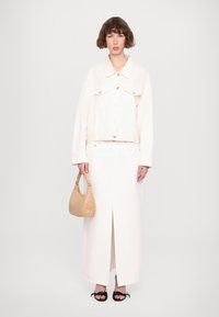 Giacca di denim bianca, gonna color crema con spacco frontale, sandali neri e borsa beige con dettaglio in rilievo "LOVE". Design minimalista e colori chiari.