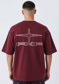 Camiseta de manga corta burdeos con un gran gráfico de estrella blanca y el texto "PXP" en la parte posterior, hecha de una tela suave y lisa.