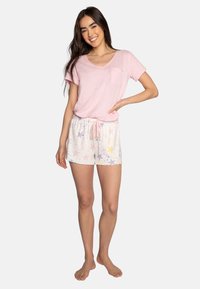 T-shirt en coton rose clair avec une poche, associé à un short blanc avec des motifs d'étoiles pastel et une ceinture à cordon.