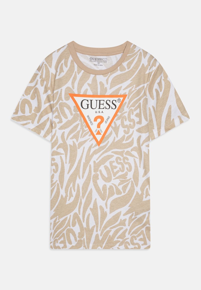 T-shirt beige avec un motif abstrait blanc, arborant un logo triangulaire orange bien en vue portant l'inscription "GUESS U.S.A." à l'avant. Manches courtes et col rond.