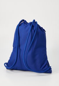 Sac à dos à cordon bleu en tissu lisse et mat avec un haut froncé et des cordons résistants et arrondis pour la fermeture. Design simple et fonctionnel.