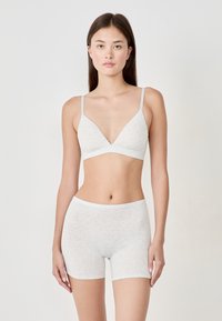 Light gray cotton bralette with thin straps and a deep V neck, paired with matching light gray short bottoms, smooth texture, minimal design.