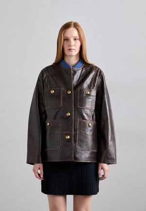 Giacca in pelle marrone con taglio dritto, bottoni dorati, quattro tasche frontali e colletto in denim a contrasto. Design con chiusura nascosta.