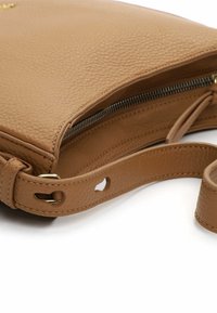 Jēra ādas plecu soma ar teksturētu virsmu, rāvējslēdzēja aizdari un noņemamu siksnu ar horizontālu caurumu detaļu.