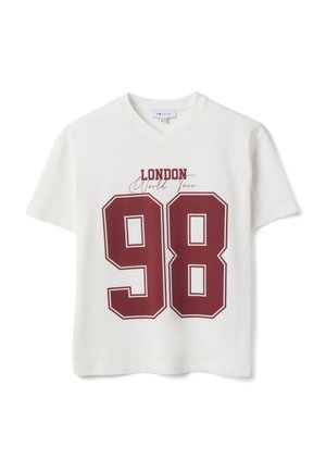 Camiseta blanca de cuello en V con un gran número "98" en color burdeos y el texto "London World Tour" encima del número en la parte delantera.