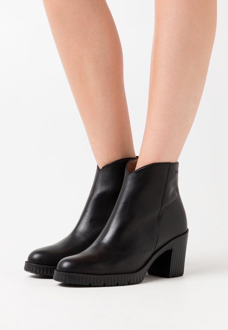 Schwarze Leder-Stiefel bis Knöchel mit glattem Finish, runden Zehen, einem Blockabsatz in mittlerer Höhe und strukturierten Gummisohlen.