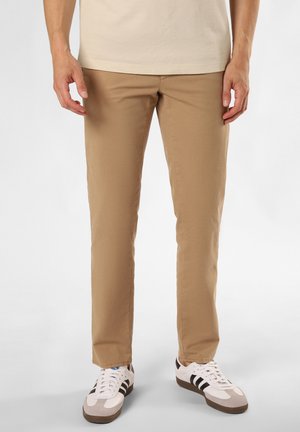 Beige Baumwollhosen im Slim-Fit mit leicht strukturiertem Stoff, kombiniert mit weißen Sneakers mit schwarzen und grauen Akzenten.