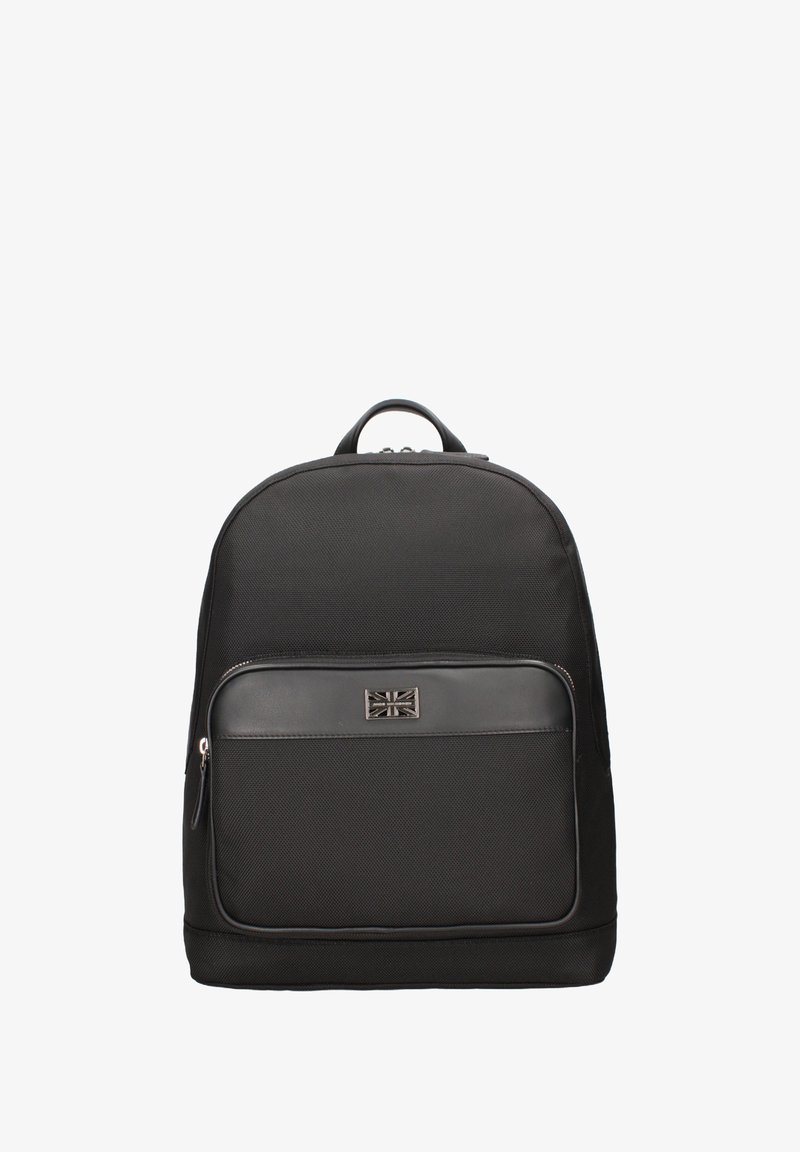 Sac à dos en tissu noir de forme arrondie, avec une poche zippée à l'avant et un petit accent métallique avec le design du Union Jack.