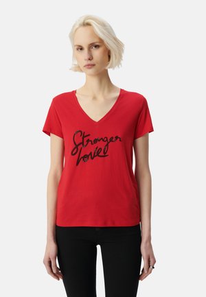 Camiseta roja de manga corta y escote en V. Presenta un texto impreso en cursiva negra que dice "Amor más fuerte". Material de algodón suave.