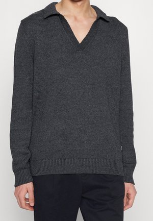 Pull en tricot gris foncé avec un col en V. Dispose de poignets et d'un ourlet côtelés, mettant en valeur un tissu texturé.