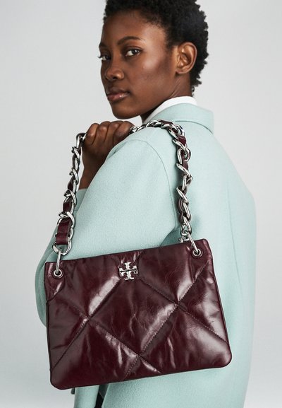 Burgundska usnjena torbica s prešito zasnovo, ki ima srebrno verigo in izrazit logotip. Gladka tekstura.