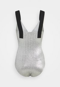 Maillot de bain une pièce argenté pailleté avec larges bretelles noires et décolleté en V profond, présenté à plat sur fond blanc.
