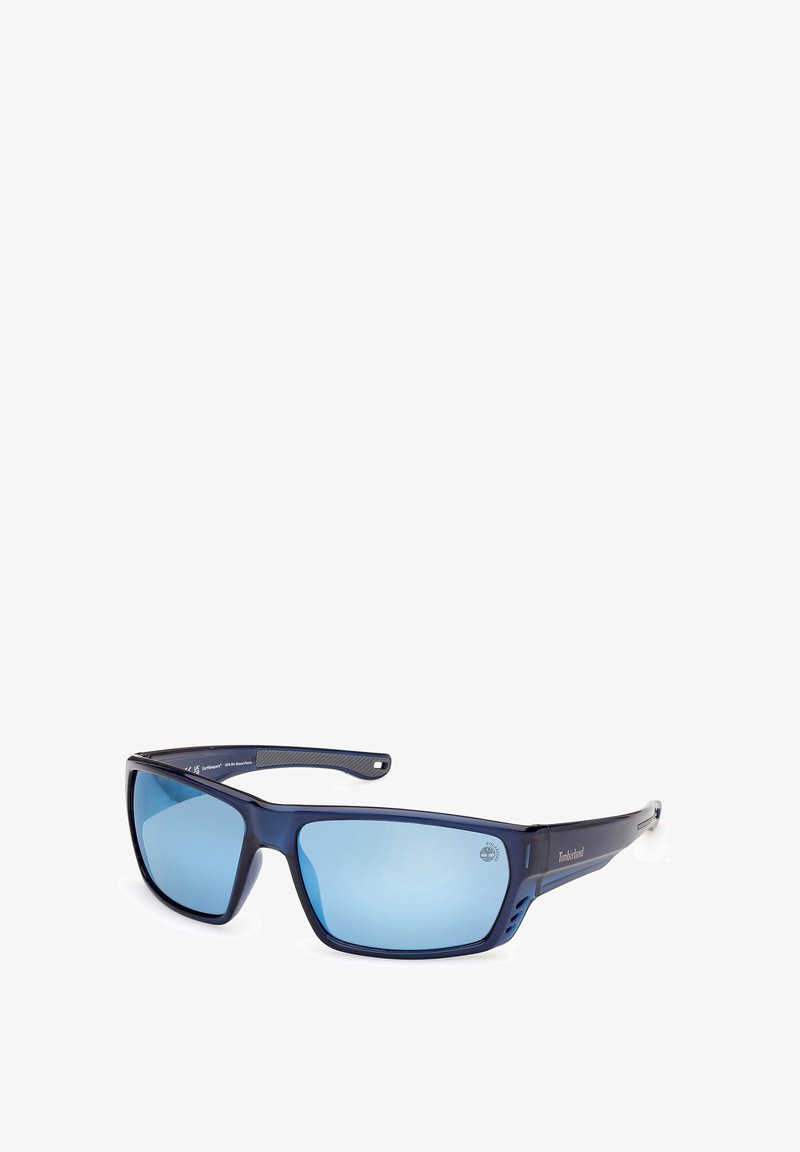Niebieskie prostokątne okulary przeciwsłoneczne Timberland z przyciemnianymi soczewkami i lekko zakrzywionymi zausznikami, przedstawione pod kątem trzech czwartych na białym tle.