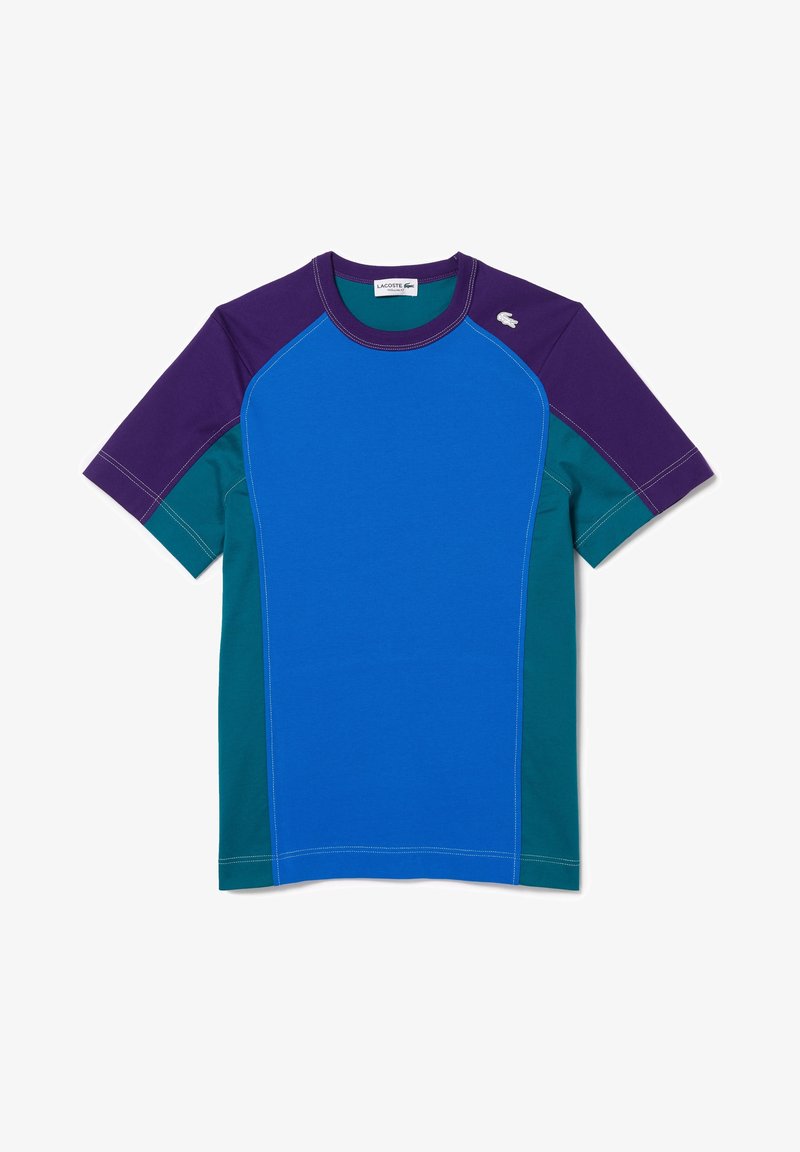 T-shirt à manches courtes en panneaux bleu, vert et violet. Avec des coutures contrastantes et un petit logo sur l'épaule gauche.