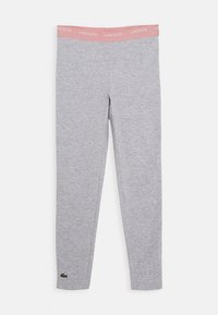 Szare legginsy z różowym elastycznym paskiem w talii, na którym znajduje się napis "LACOSTE" oraz zielony logo krokodyla umieszczone blisko dolnego szwu na lewej nodze.