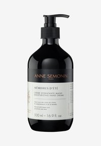 Black pump bottle containing 500 ml of moisturizing hand cream, with a textured black pump, and a white label featuring black text and floral accents.